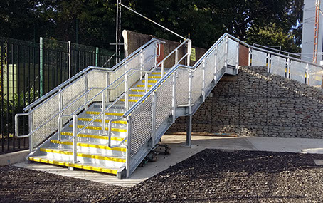 A galvanised escape staircase with grill infill panels. Designed, supplied & installed by ASH Construction Ltd.